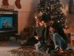 Christmas Movies Couple sat playing with puzzle in front of a tv. Behind them there is a christmas tree and stockings hanging on the wall.