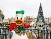 Christmas at Disneyland Paris Donald Duck standing on a balcony pointing towards a large Christmas tree in the distance