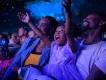 Frozen Sing Along Celebration A little girl smiling and holding her arms up while sat with her mum and dad in a theatre