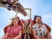 Two adults laughing and screaming with their hair flying while riding a high-speed roller coaster at Universal Orlando Resort, illustrating the kind of thrill ride experience you secure by booking tickets in advance.