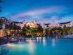 Illuminated lagoon-style swimming pool and tropical architecture at a premium Universal Orlando Resort hotel at night.