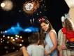 A family wearing Mickey and Minnie ears watches a spectacular nighttime fireworks display over a lit-up theme park at Walt Disney World Resort.