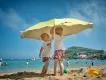 Children playing with beach umbrella on family summer vacation.