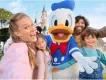 A family smiling together with a Donald Duck character at Disneyland Paris