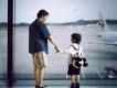 A father and son looking out the window at an airport