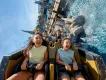 Riders laughing and screaming as their coaster splashes through water on Hiccup's Wing Gliders, Isle of Berk