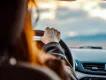 Over-the-shoulder view of a person holding a steering wheel while driving