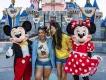 Two friends laughing while posing with Mickey Mouse and Minnie Mouse in front of Sleeping Beauty Castle