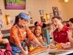 Server presenting food to a laughing group of guests at the Sports Bar & Lounge presented by Coca-Cola, Disney Village