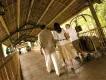 A couple walking along a covered bamboo walkway at Loews Royal Pacific Resort while a hotel staff member pushes a luggage cart