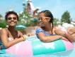 Two smiling women floating together on a colorful inflatable inner tube in a water park pool