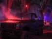 A dark pickup truck with red smoke rising from the open hood parked in swampy woods filled with neon lighting
