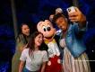 Two guests taking a selfie with Mickey Mouse at night
