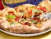 A slice of Harvest Moon pizza with fresh toppings being lifted from a plate at Pizza Moon in Universal Epic Universe