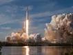 A SpaceX Falcon Heavy rocket launching from the pad, surrounded by large plumes of exhaust