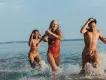 Three friends laughing and splashing in the sea on a summer holiday.