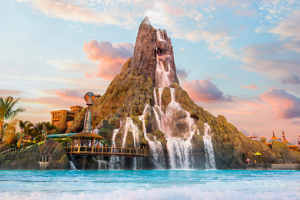 A large volcano spilling water into a water park wave pool