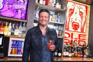 Blake Shelton holding a glass of sangria behind a bar