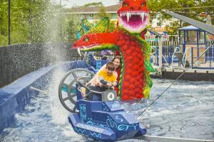 A woman and child getting splashed in a boat ride vehicle in front of a giant Lego sea serpent 
