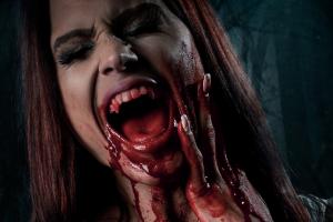A woman screaming and holding her face with blood on her hands and chin