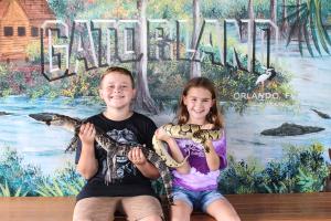Boy holding a baby alligator and girl holding a snake at Gatorland