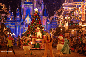 Mickey Mouse standing in front of a Christmas Tree on a parade float. Characters such as Peter Pan, Donald Duck and Pluto dance in front of it