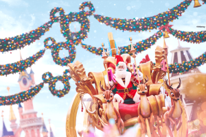 Santa Claus on a parade float being pulled by mechanical reindeer, with Mickey Mouse wreaths and Sleeping Beauty Castle in the background