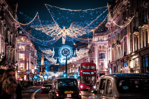 Black taxis and a red London bus driving down Oxford Street underneath the Christmas lights