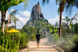 A child in a wetsuit walking along a path lined with plants towards the volcano at Volcano Bay