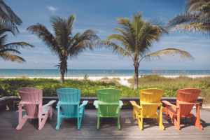 A row of different coloured beach chairs looking out onto the beach