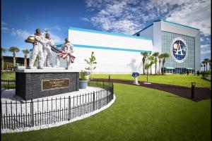 A statue of three astronauts holding an American flag in front of a building with a large sign reading Apollo NASA