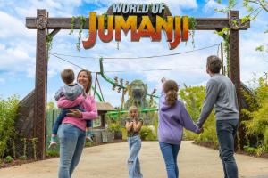 A family standing in front of a sign reading World of Jumanji. One child is holding her face as if in shock