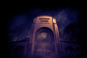 A large archway reading Universal Studios Hollywood surrounded by fog at night