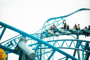 People riding a coaster with ride vehicles shaped like snowmobiles on a blue track