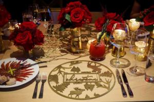 A table decorated for Christmas with red flowers and gold place settings