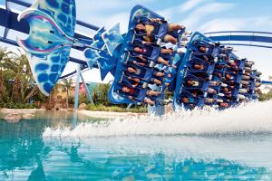 Ride shaped like manta ray in motion, curving round bend on top of lake with water being sprayed up towards the riders