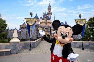 Mickey Mouse standing in front of Sleeping Beauty Castle at Disneyland Resort