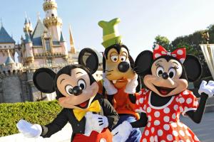 Micky, Minnie und Goofy posieren vor dem Dornröschenschloss in Disneyland Kalifornien