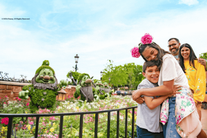 A boy and girl hugging next to topiaries of the seven dwarves from Snow White