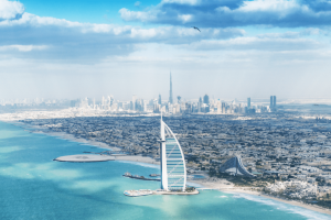 The Burj Al Arab on an island out at sea shaped like a boat sail and in the background you can see the whole city skyline.