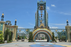 Grand entrance with a semicircle portal opening and above there's a statue of a planet and star constellation.