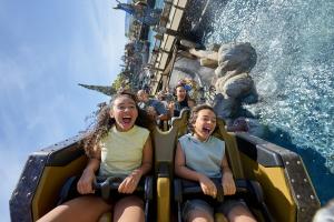 Two kids riding a rollercoaster over water