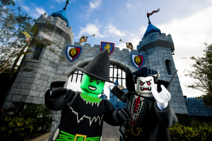 A lego green witch and a lego vampire at the gates of a castle.