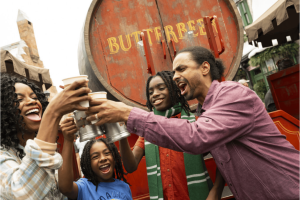 An excited family raising Butterbeer beverages in celebration, capturing an unforgettable and unique experience in The Wizarding World of Harry Potter at Universal Orlando Resort.
