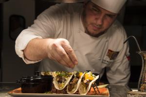 A chef garnishing fresh gourmet tacos on a platter at a Universal Orlando Resort restaurant.