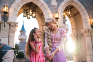 A young girl meeting Rapunzel in front of the castle at Disney World