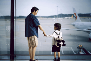 A father and son looking out the window at an airport