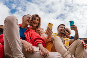 Group of friends using their smartphones while laughing.