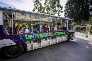 Guests smiling and waving from the Universal Studios electric tram during the studio tour