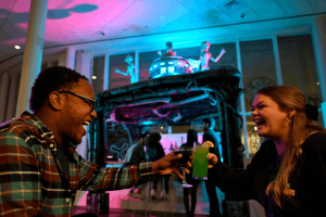 Two guests laughing and clinking colorful themed cocktails at a Universal Orlando Resort hotel Halloween Horror Nights bar experience